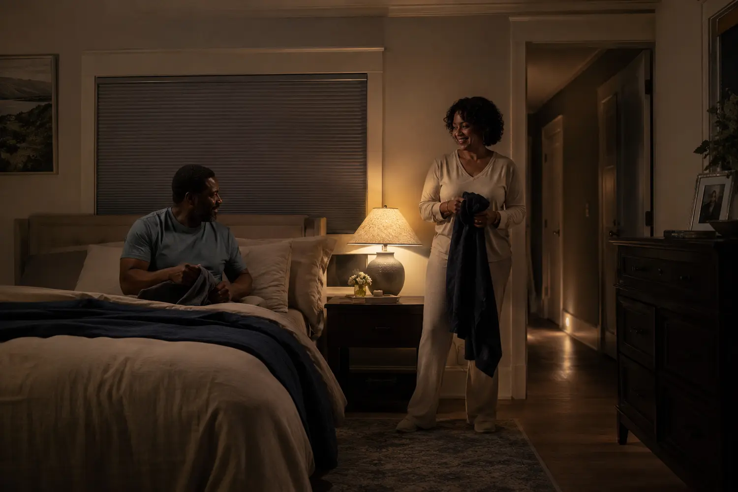 Black couple preparing for bed with low path lighting and a closed motorized shade